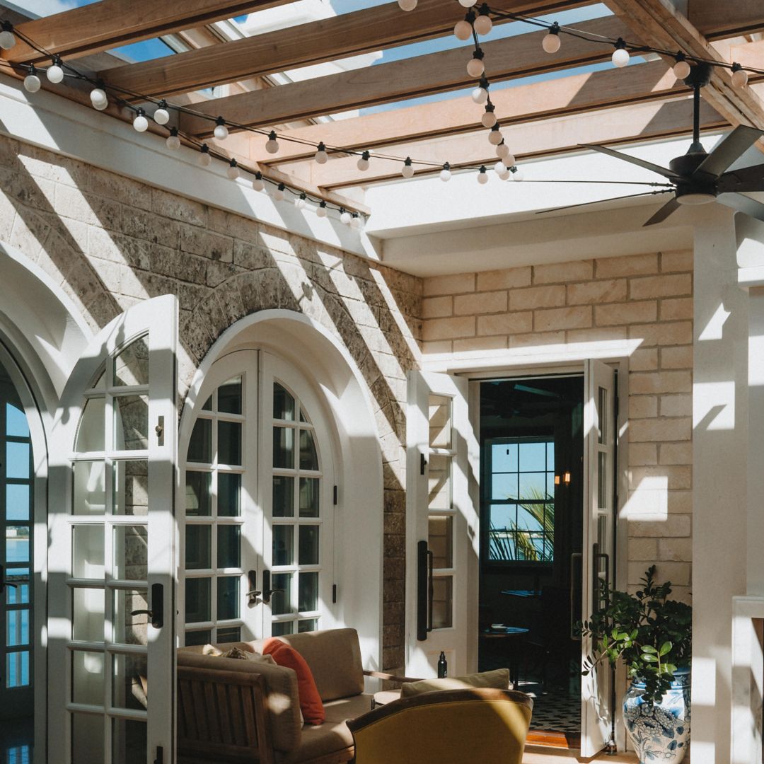 The interior of Conservatory Bar features a cozy couch and a veranda that welcomes streams of sunlight.