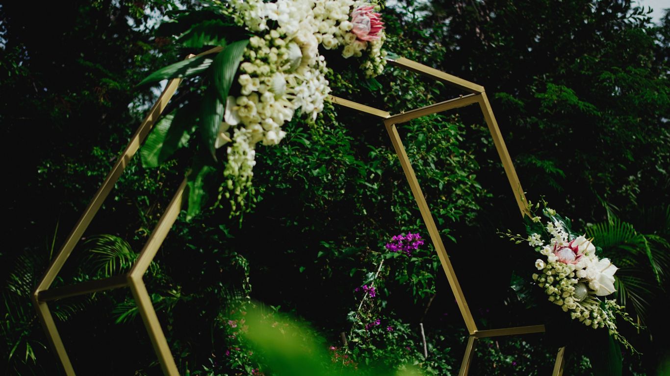 octogon shaped wedding alter decorated with white and pink flowers in a lush green setting