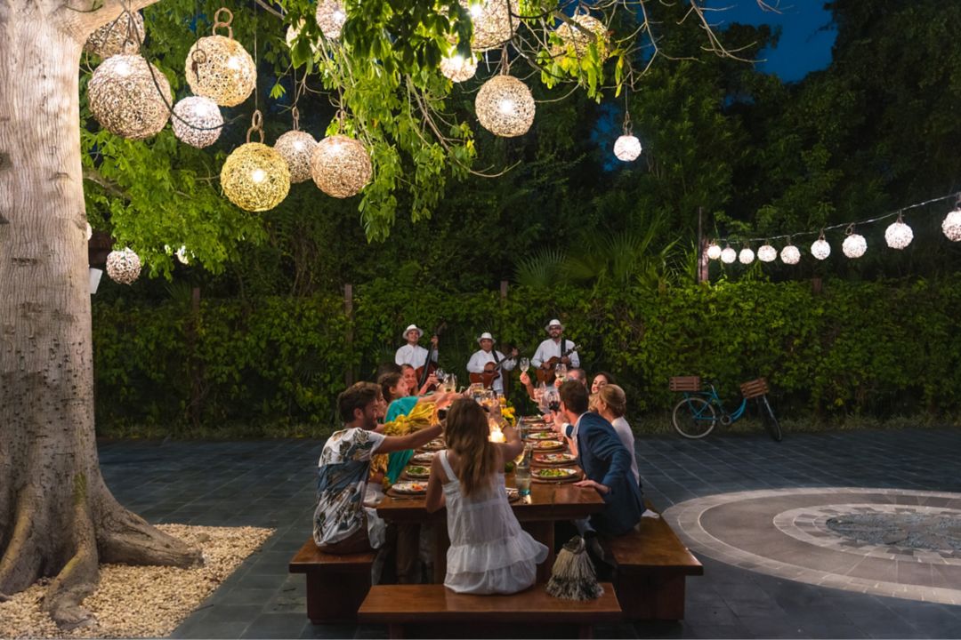  La gente se reúne alrededor de largas mesas riendo durante una cena familiar al-alfresco