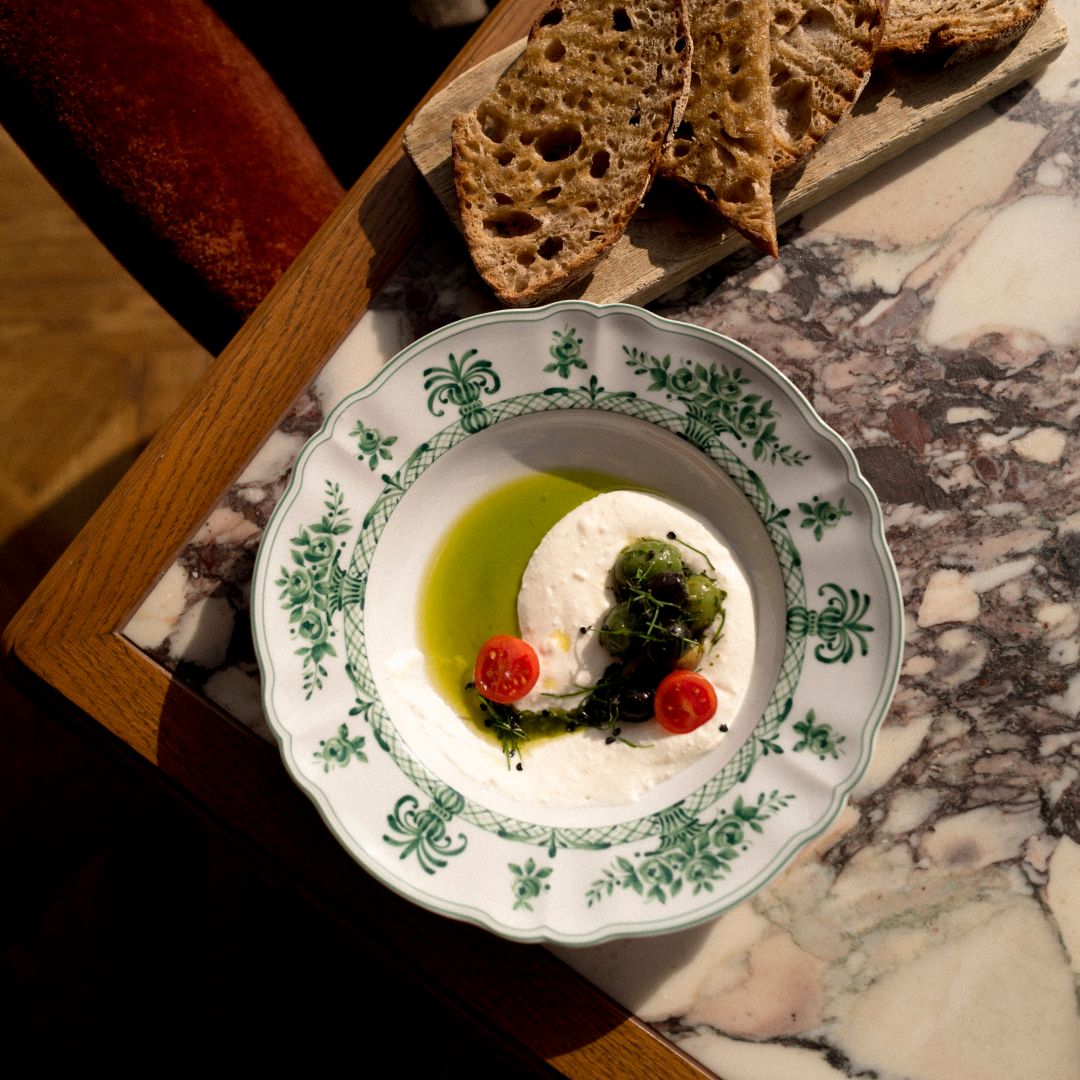 Ein mit Blumen dekorierter Tisch und ein wunderschöner Ausblick auf die historischen Gebäude der Wiener Altstadt im Neue Hoheit Restaurant.