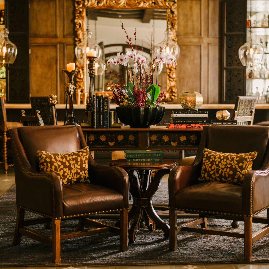 A tequila bar with leather chairs, a table with books, and a mirror in the background.