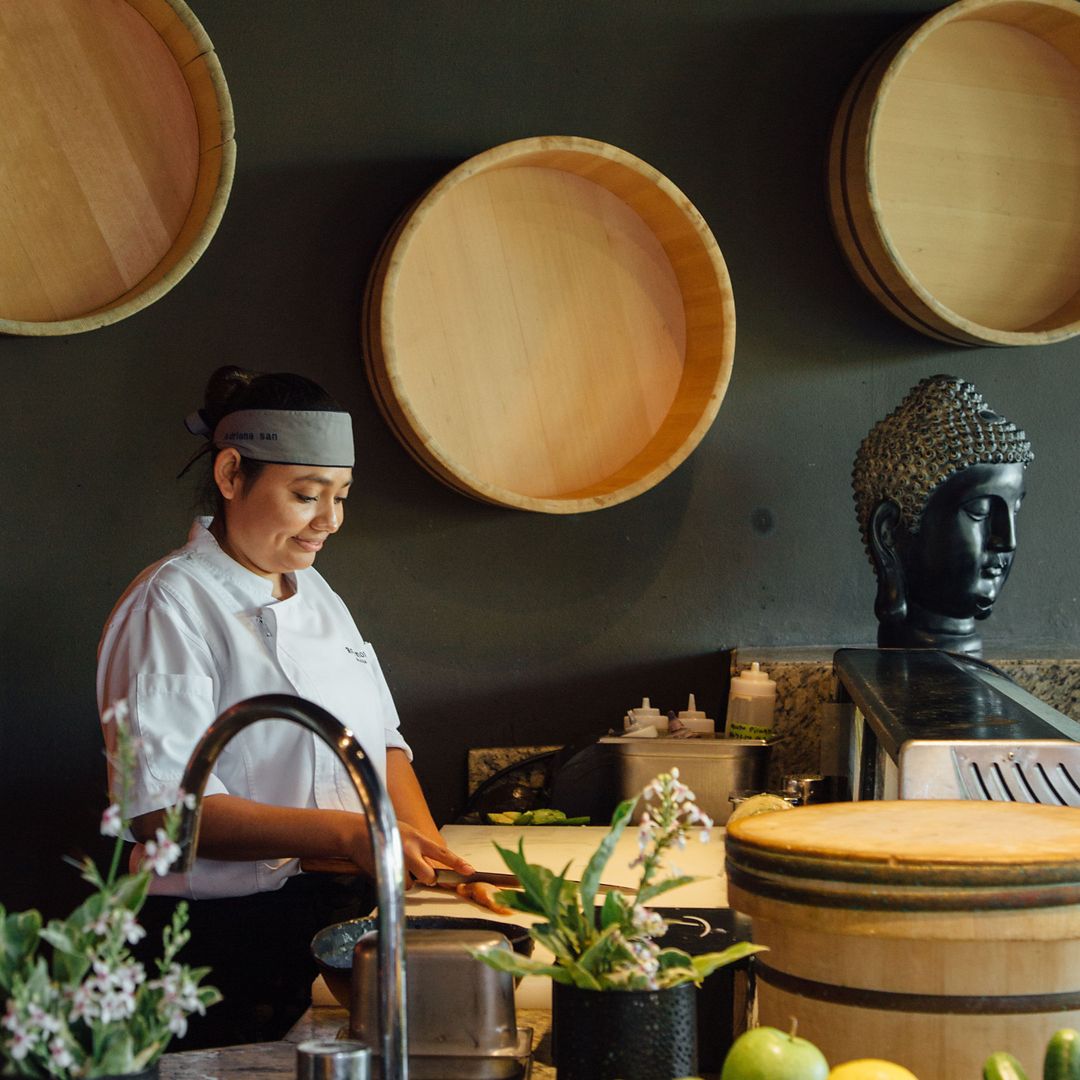 Chef preparing ingredients with a knife behind the bar at Agave Azul.