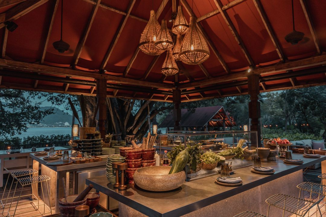 A hotel dining area featuring a chandelier and a long table set with plates.