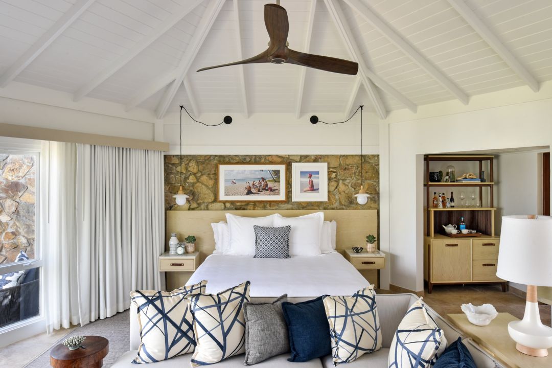 Rosewood bedroom with a king-size bed, decorative pillows, a seating area, and a bar cabinet.