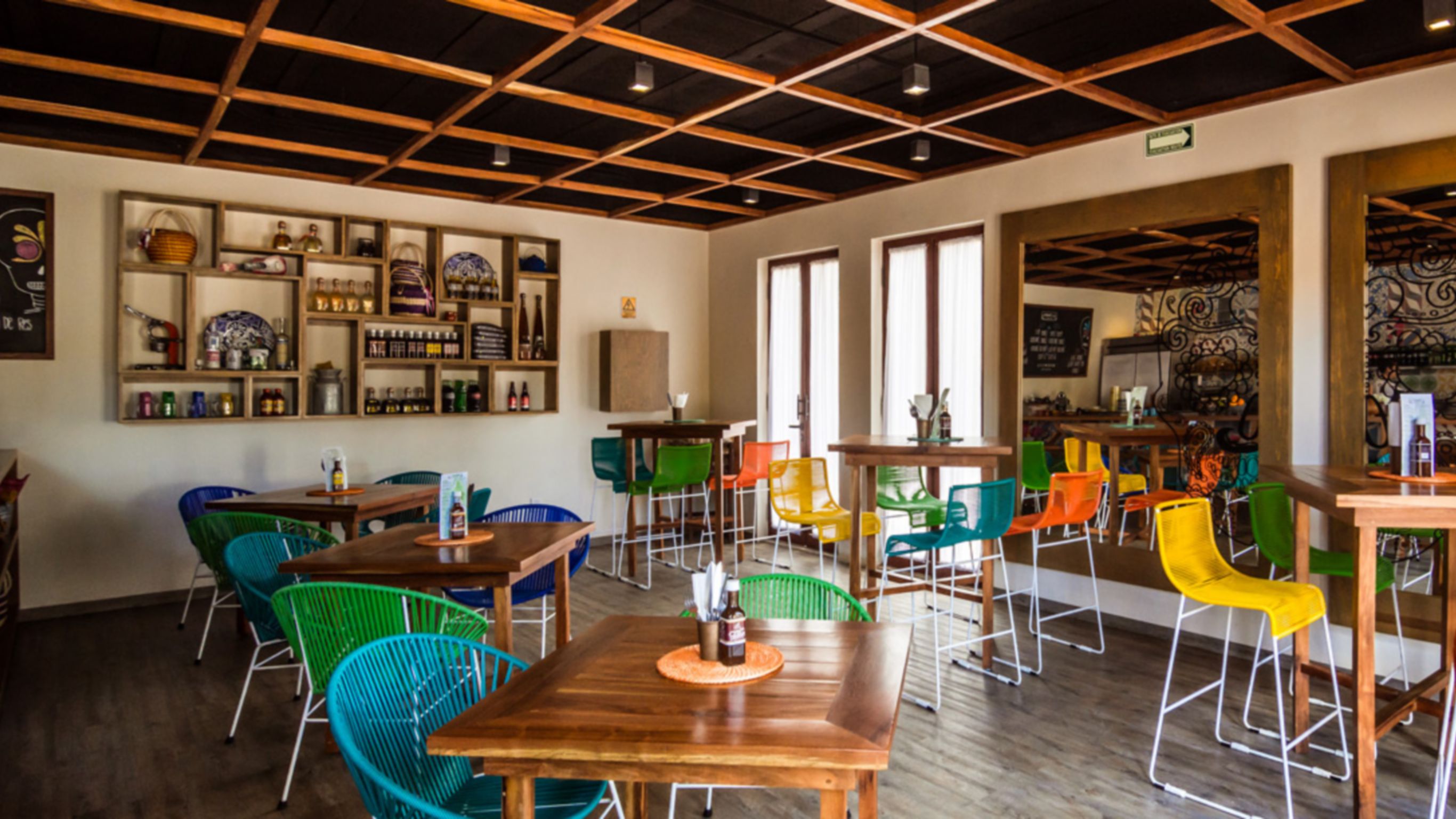 Balcão do La Fondita com garrafas de mezcal e prateleiras com molhos, cestas coloridas e refrigerantes