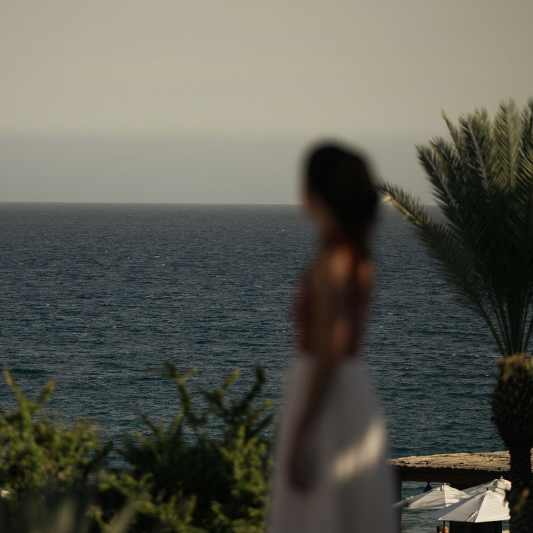 A woman in a dress standing by the sea, admiring the landscape.