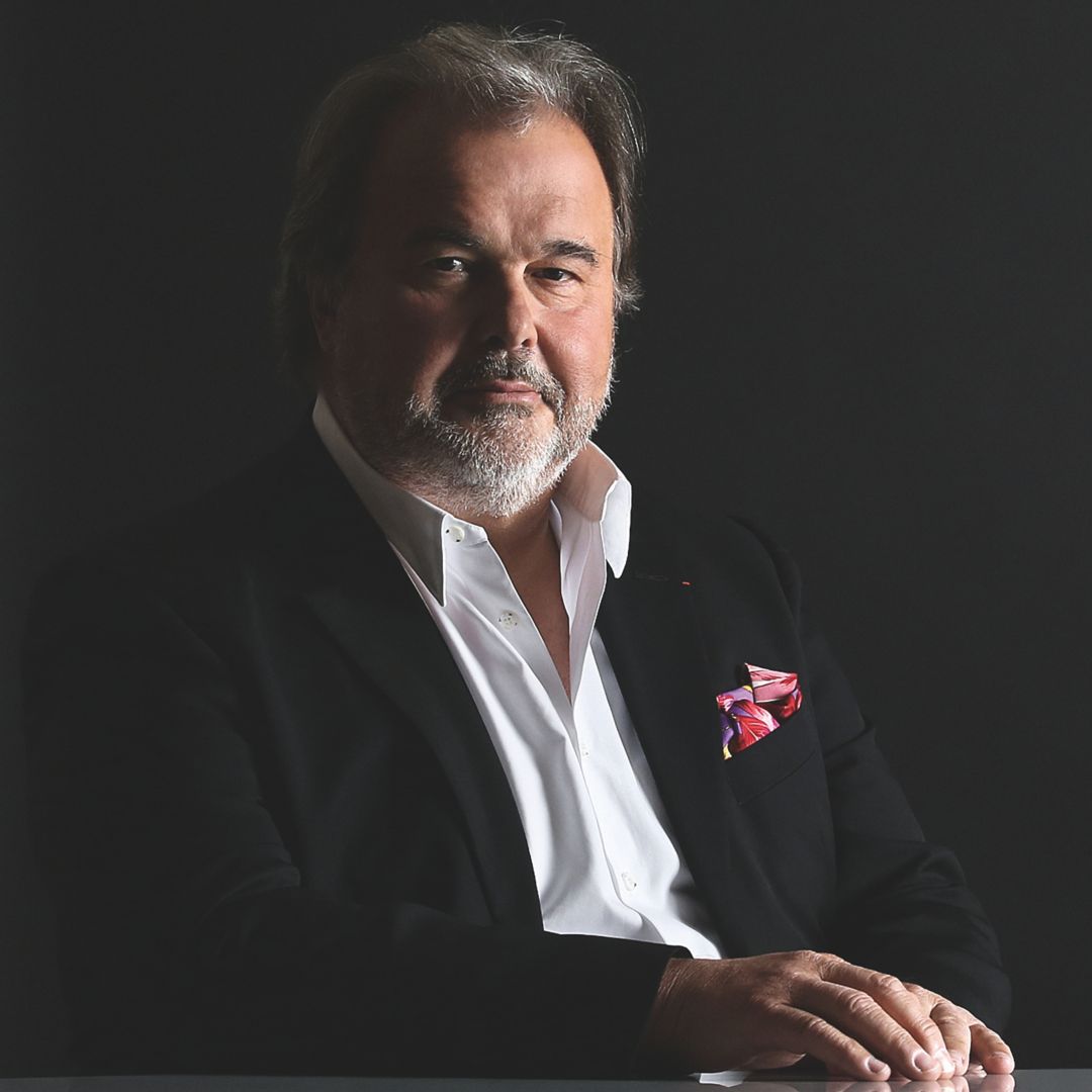 Portrait of Pierre Hermé, a renowned pastry chef, dressed in a suit with a colorful pocket square.