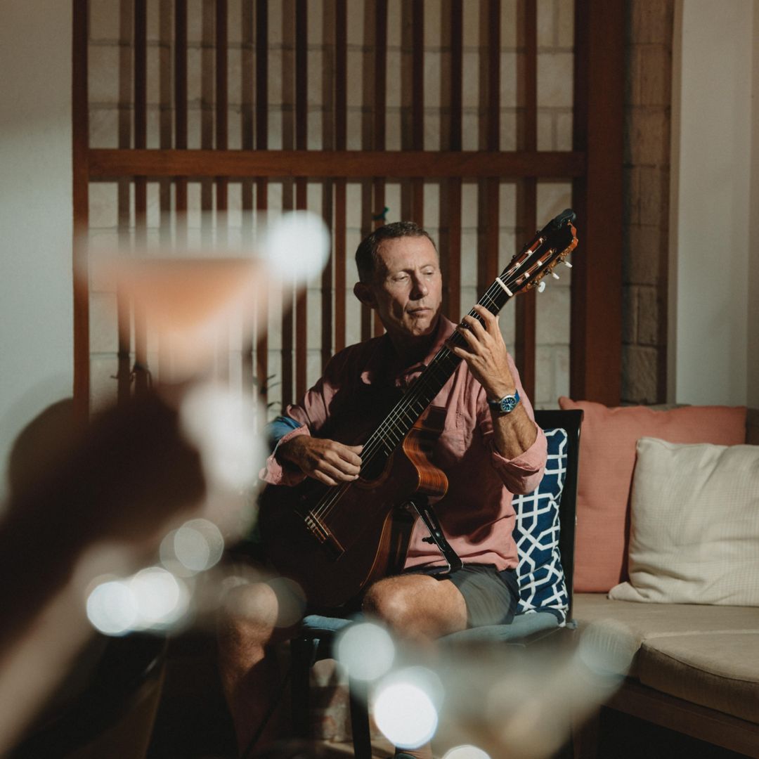 Foreground pink cocktail cheers to guitarist playing music in background