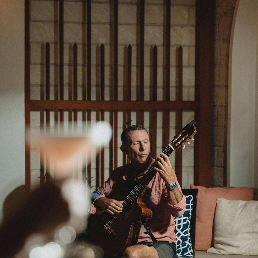 Foreground guest toasting Steve Crawford playing acoustic guitar in background