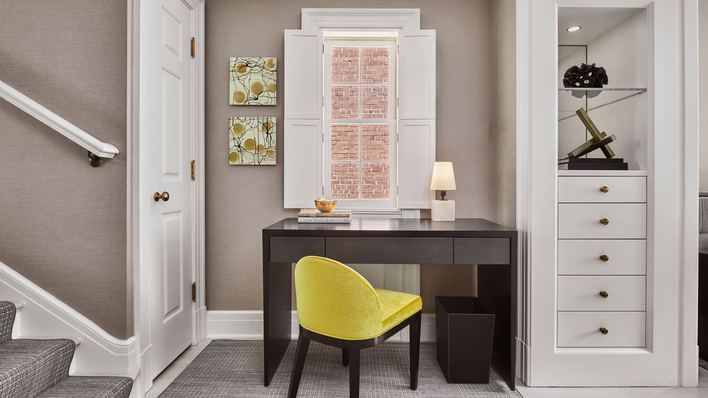 A small office area with a desk and a yellow  chair located near a staircase.