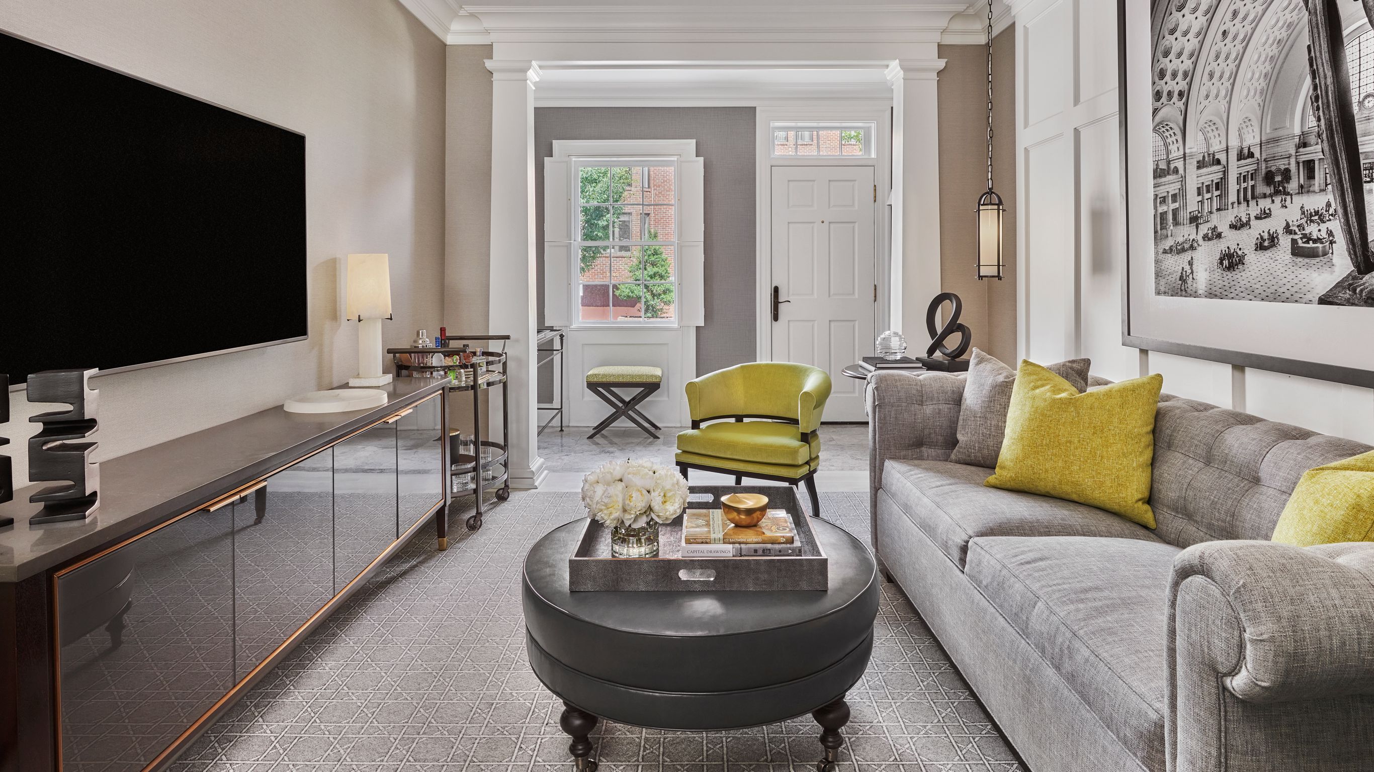 A townhouse foyer view from the living space with a sofa, armchairs, a coffee table, and a TV.