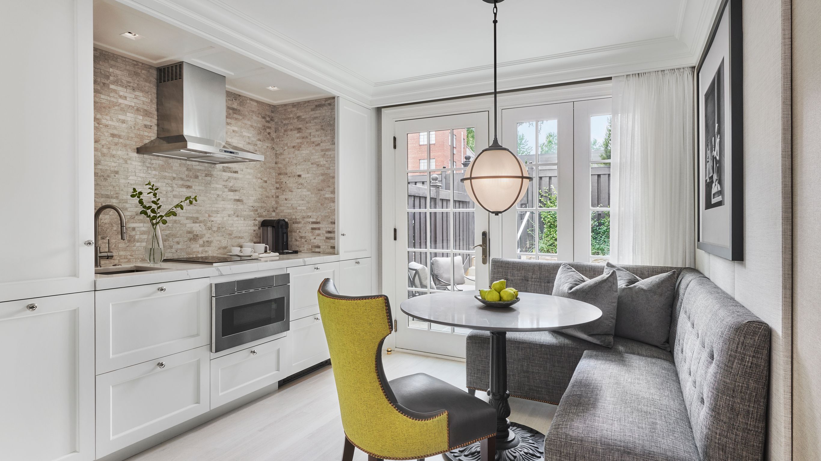 A townhouse kitchen with a dining area, featuring a table, sofa seating, and a view of the backyard.