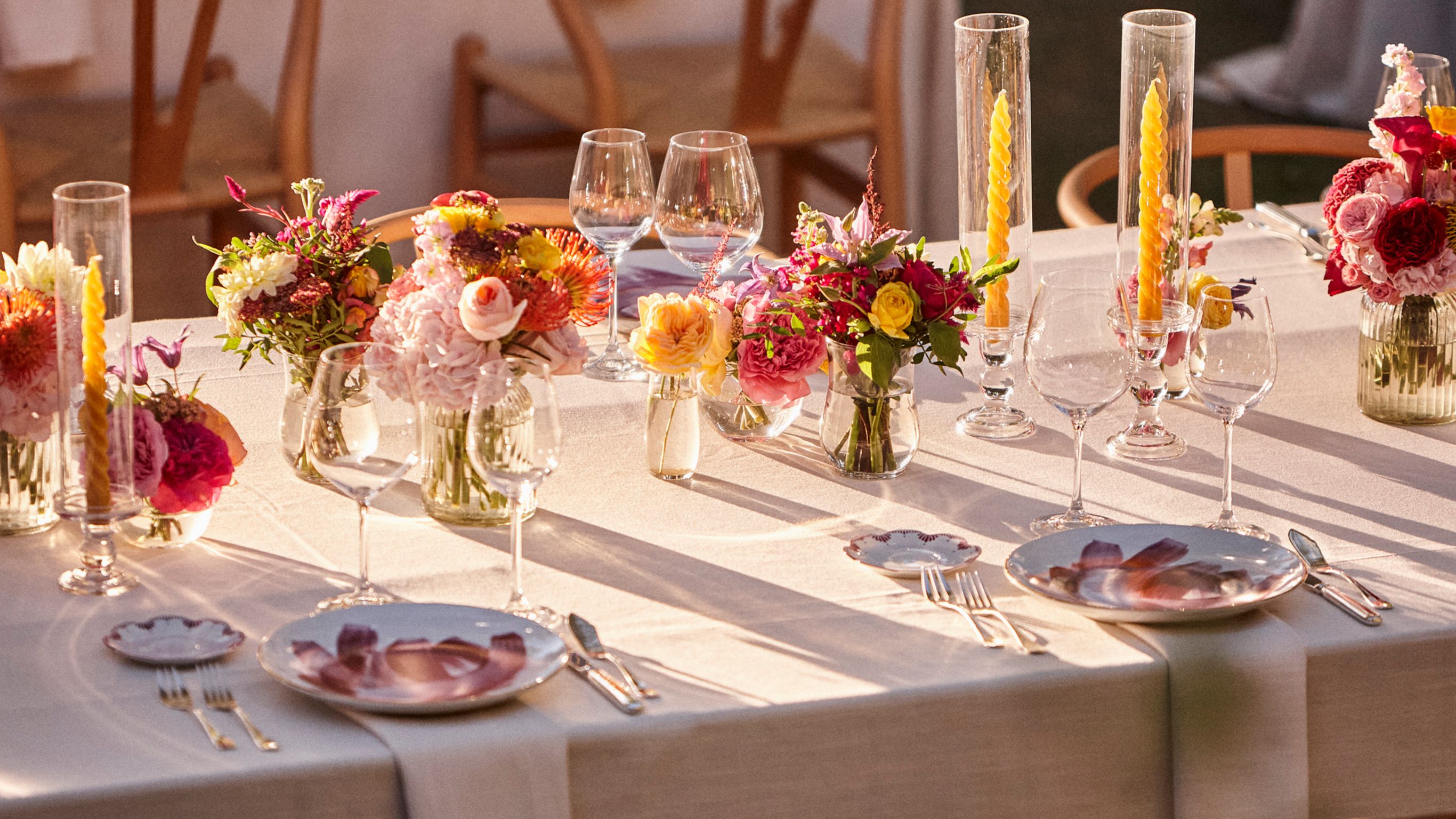 wedding table with sun and shades, white tablecloth, pink and yellow flores, candles and beautiful plates