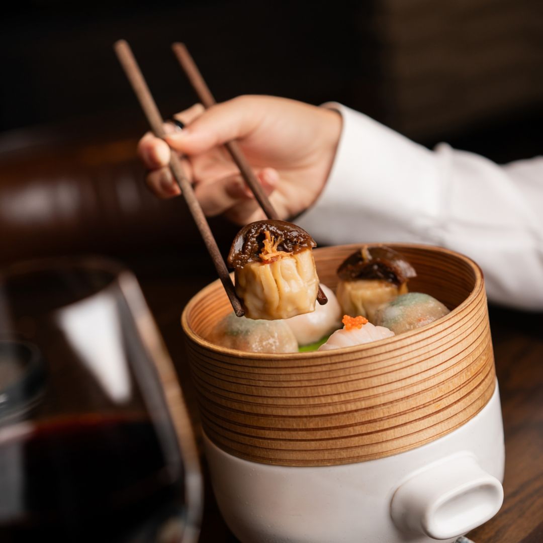 A close-up of a bamboo steamer filled with  dim sum, including a dumpling.