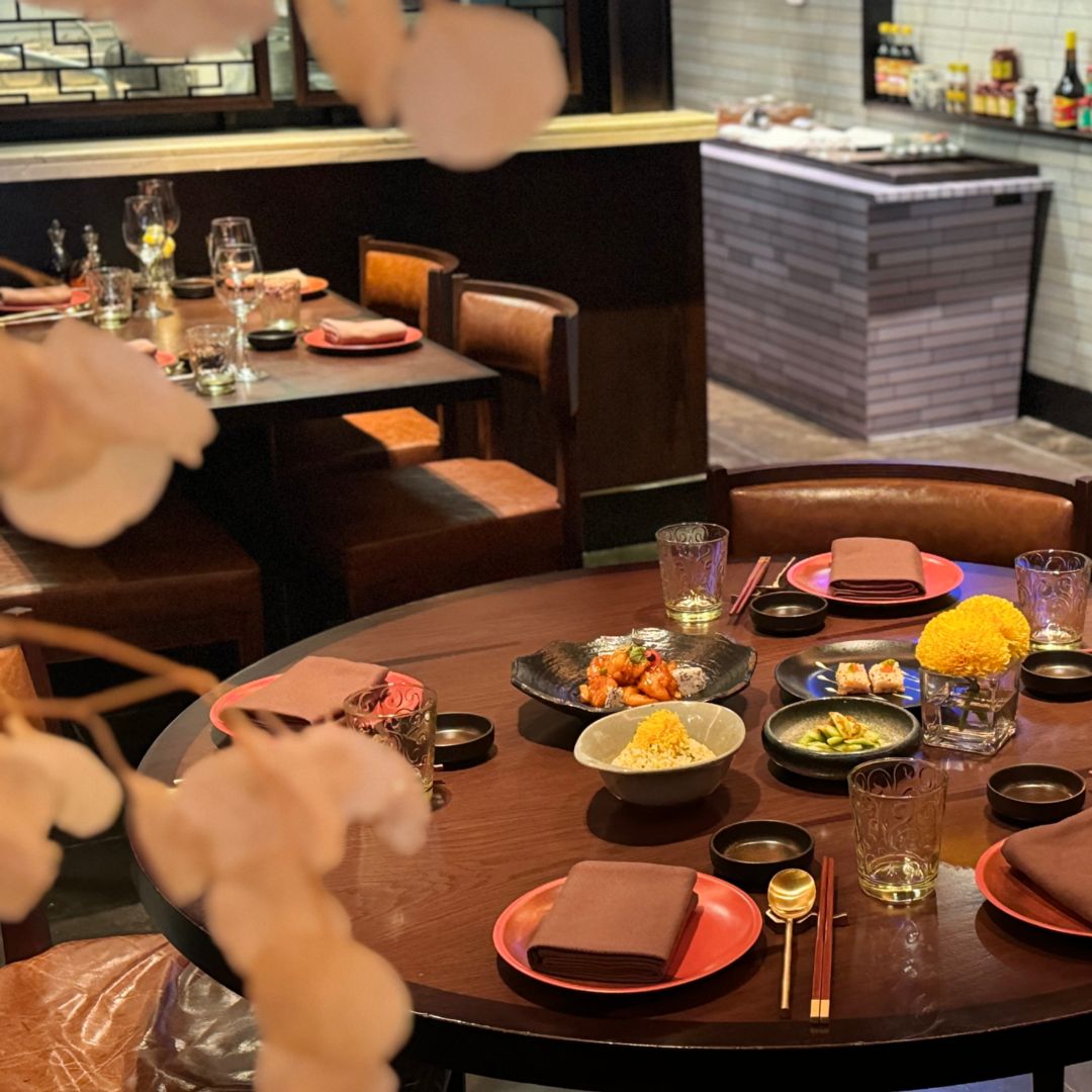 A round dining table set with various Asian dishes, including noodles, dumplings, and vegetables.
