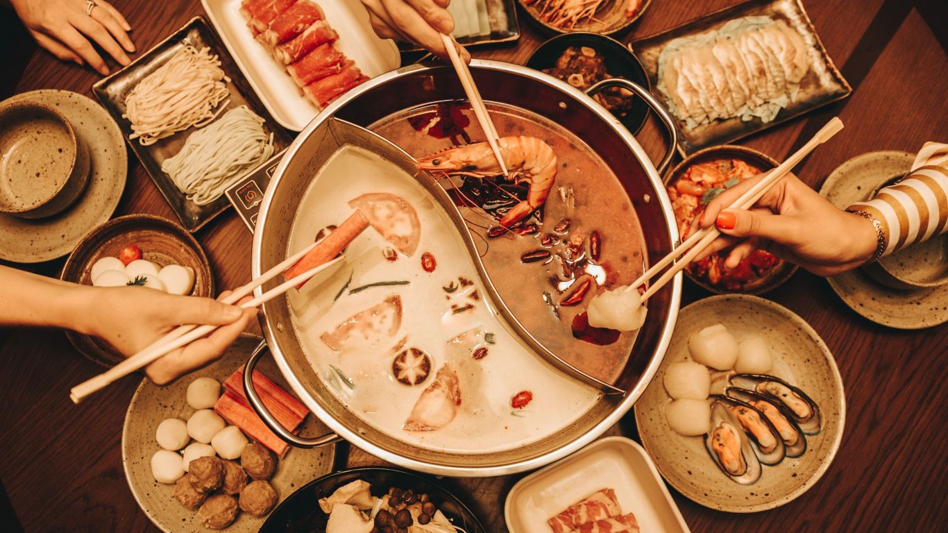 A steaming hot pot filled with an array of fresh ingredients, surrounded by friends and family, celebrating the Mid-Autumn Festival with a delightful brunch