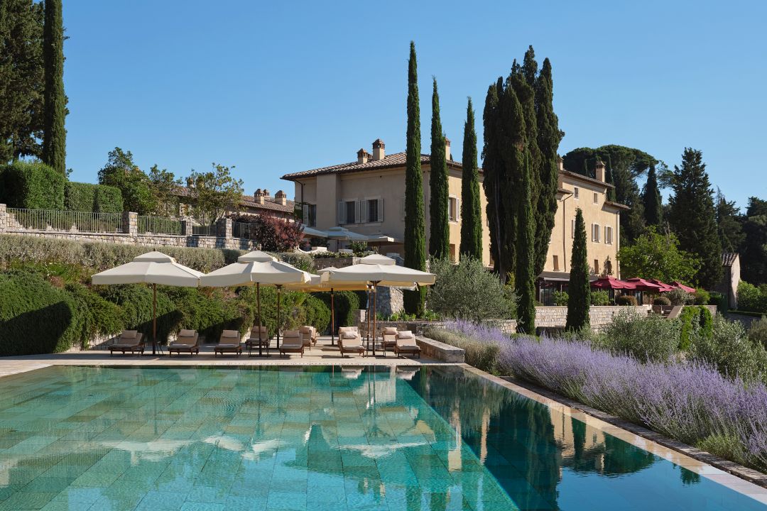A resort pool surrounded by lounge chairs and umbrellas set beneath a clear blue sky.
