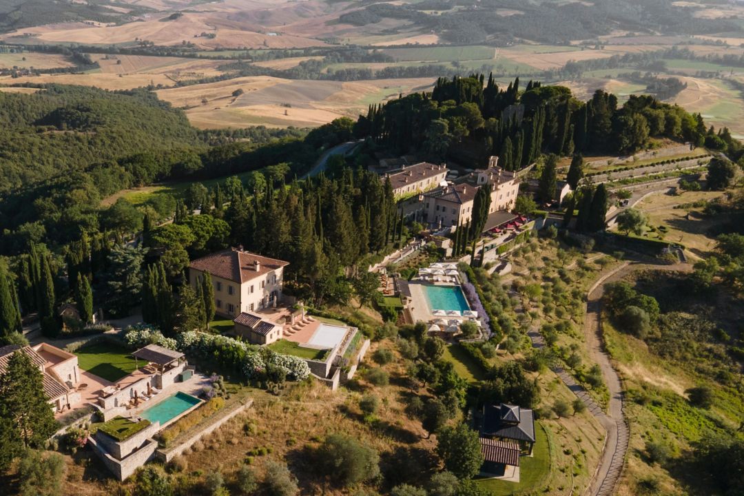 View of the luxury Tuscany hotel pool area,  framed by cypress trees.