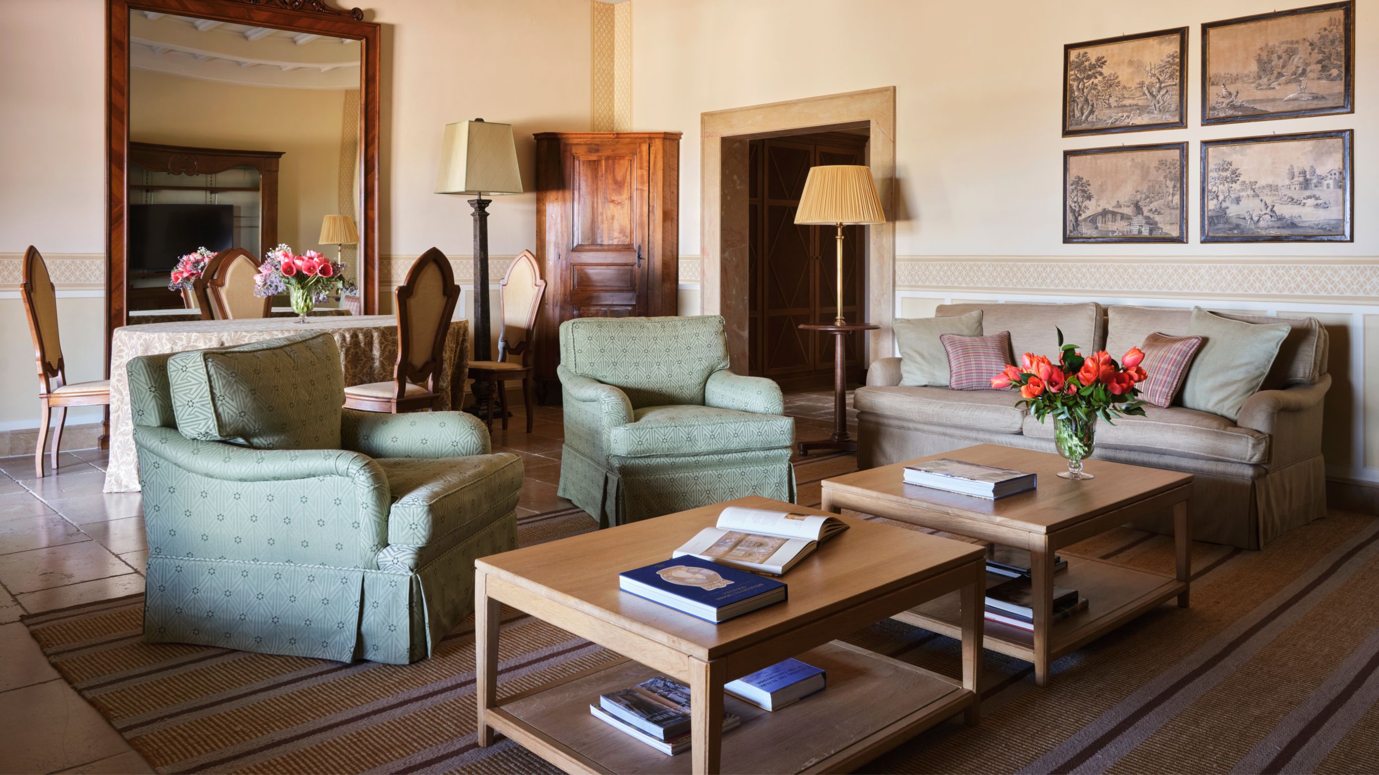 Living room with green armchairs, a sofa, coffee tables and framed artwork