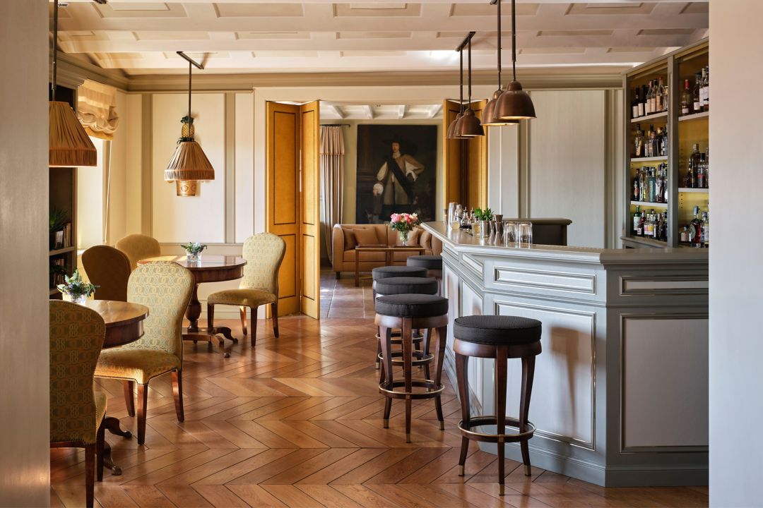 A luxury lounge with a bar, seating, and a painting, featuring classic decor and warm lighting.