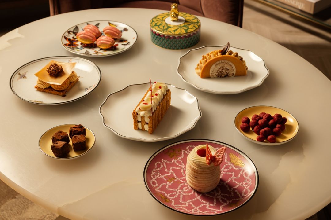 Beautiful pastries and delicacies arranged on decorative plates on a white table.