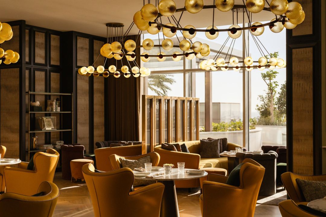 A fine dining restaurant in Doha featuring yellow armchairs and modern chandeliers.