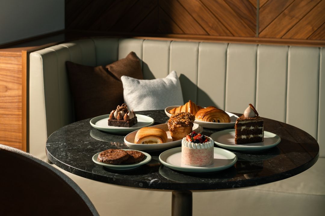 A selection of pastries, including cakes and cookies, set on a dark table.