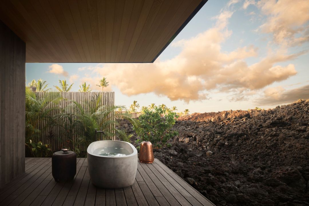 Outdoor soaking tub on a private deck, overlooking a dramatic volcanic landscape at a Big Island resort.