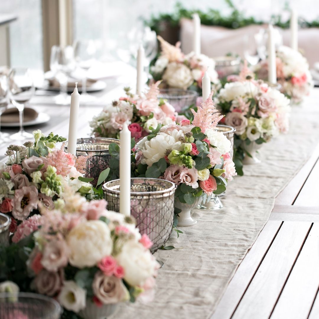 Long table with pink and white floral centerpieces arranged for a wedding reception.