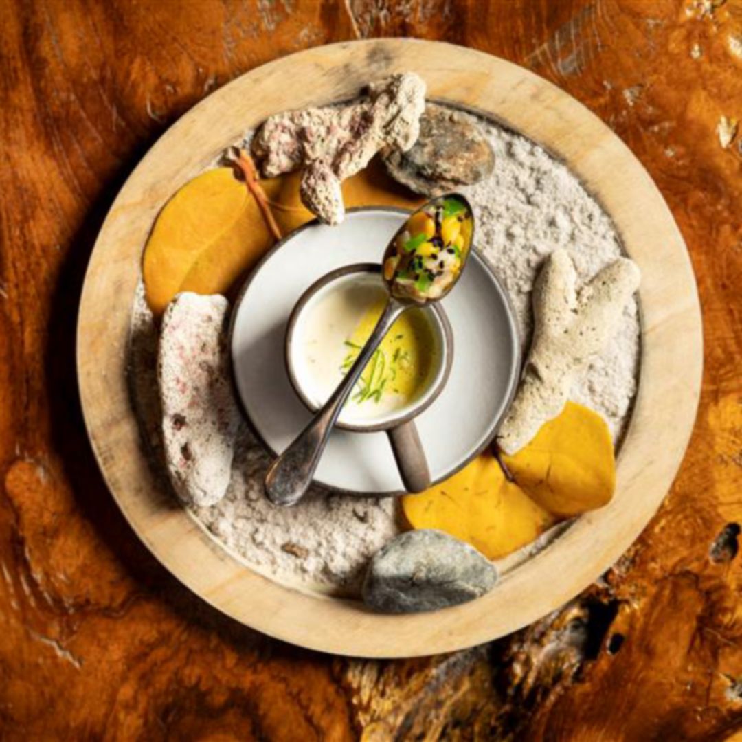 A beautifully presented dish with a spoon on  a wooden table.