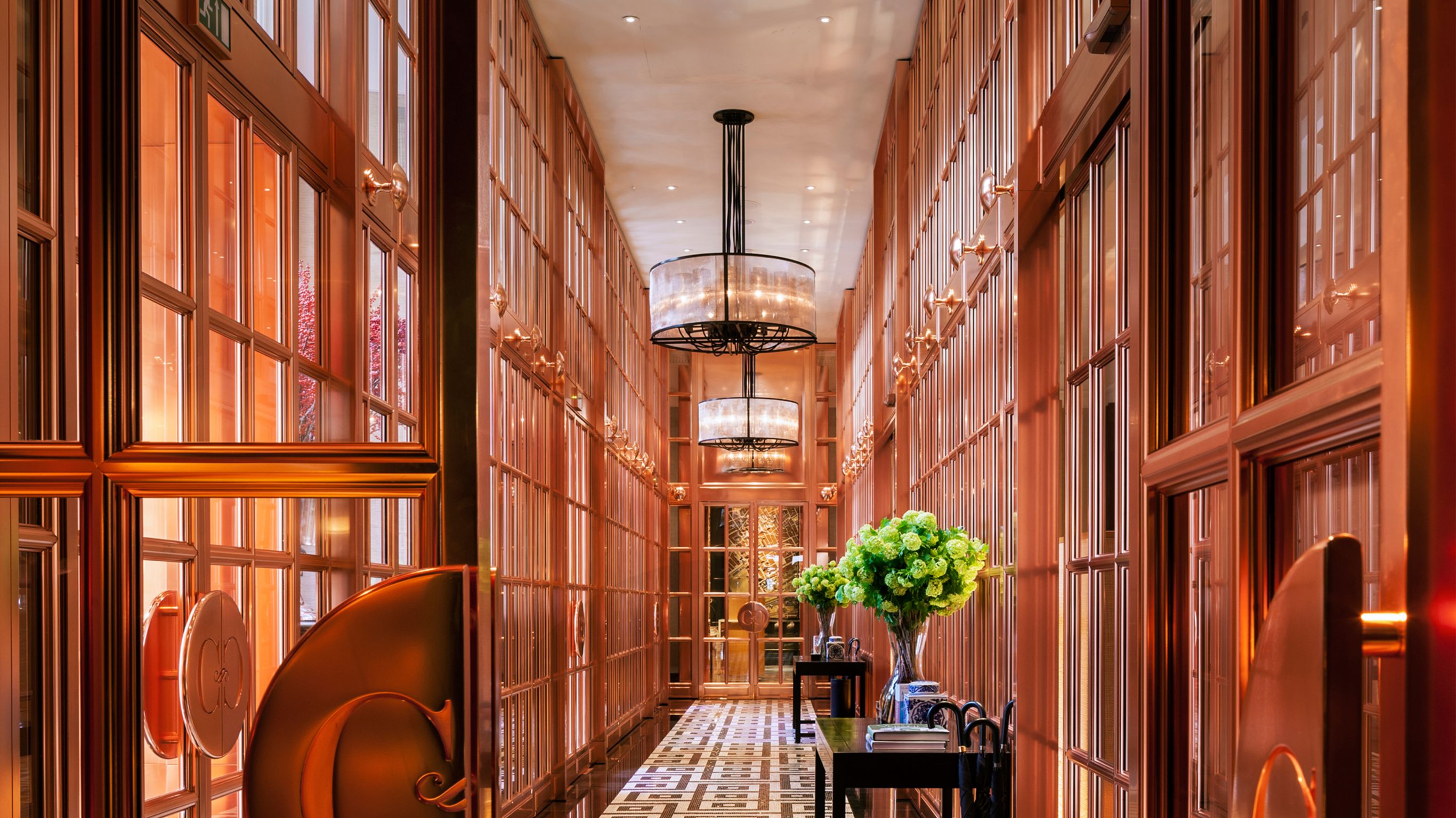 a hallway with glass walls and a chandelier