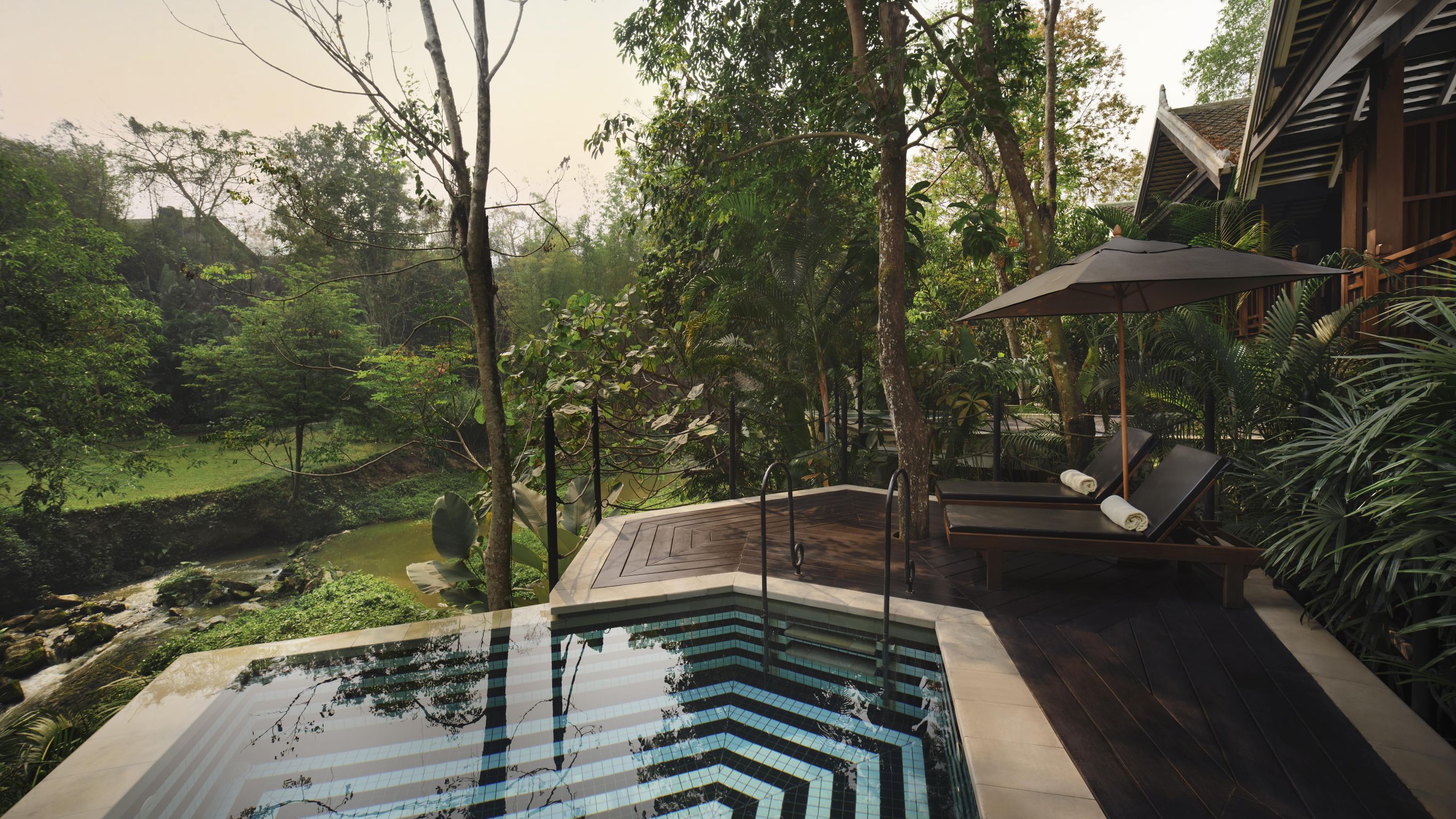A private plunge pool and two lounge chairs overlooking a river in Luang Prabang.