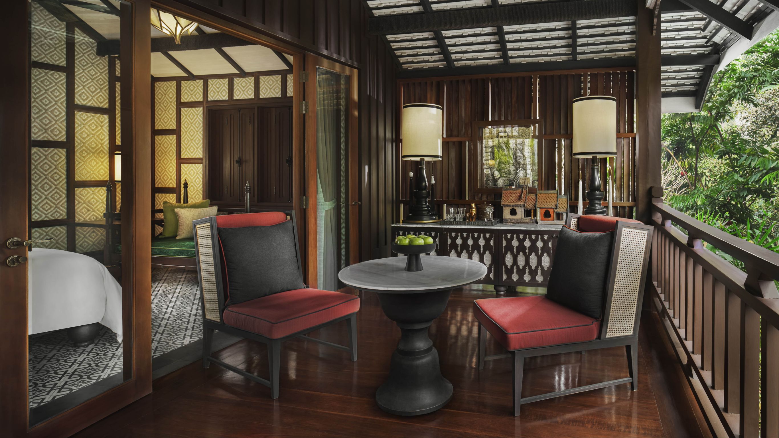 Two red cushioned chairs on a balcony of a luxury hotel suite designed by Bill Bensley in Luang Prabang.