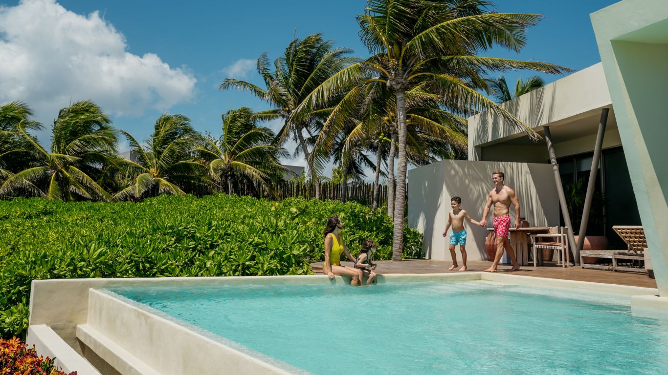 Familia de cuatro disfrutando de la piscina del Beachfront Presidential de Rosewood Mayakoba
