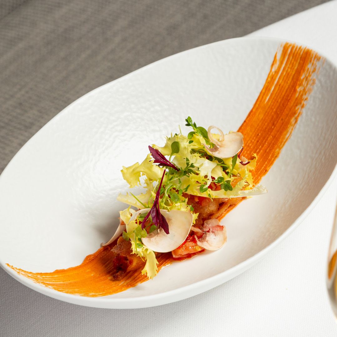 A vibrant dish featuring a creamy orange sauce garnished with greens and herbs