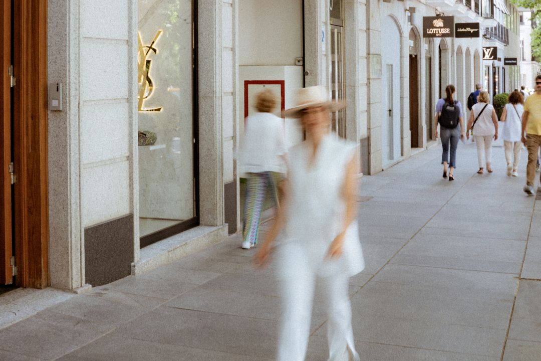Busy street scene with people walking past luxury stores like Yves Saint Laurent
