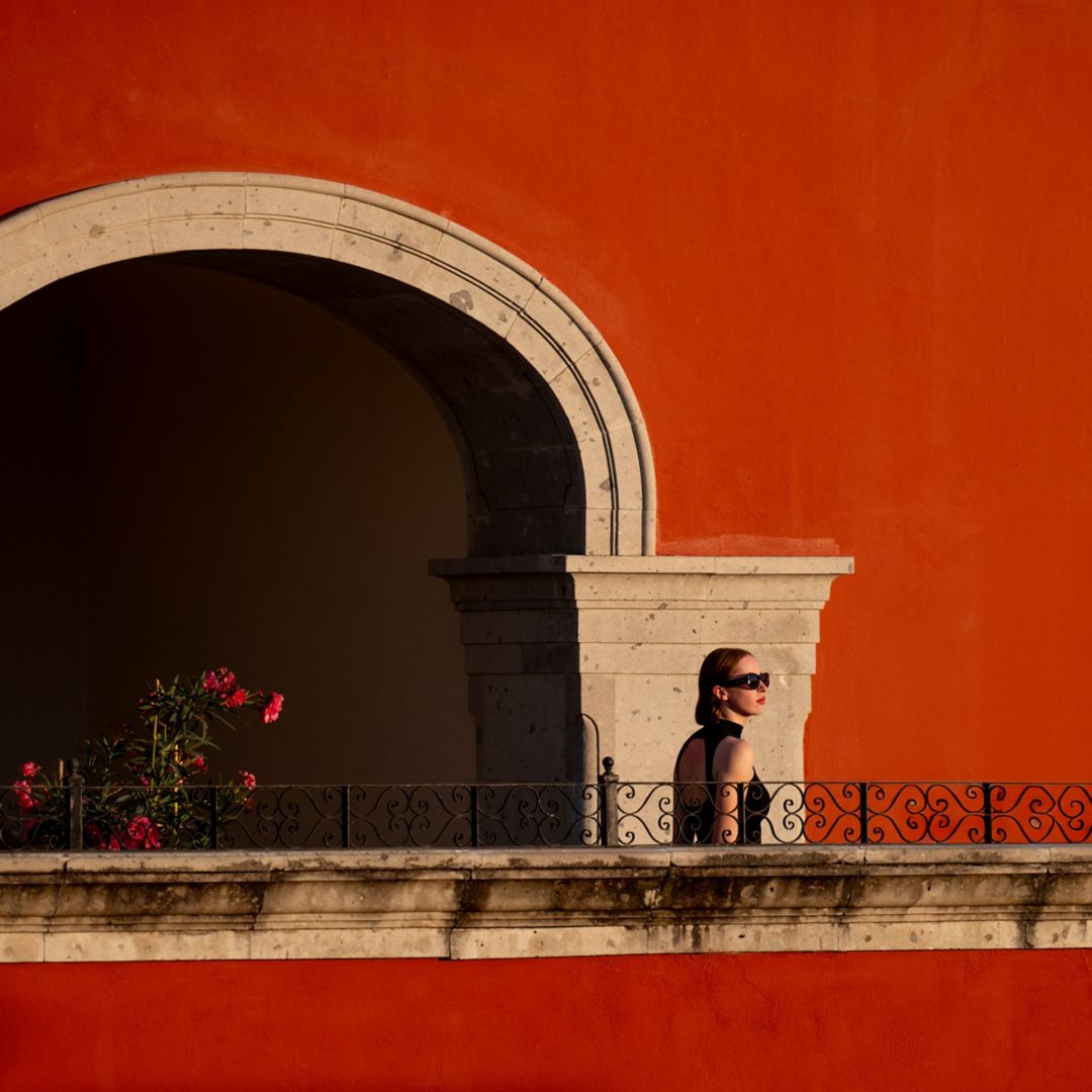 Lifestyle image of woman walking along balcony corridor