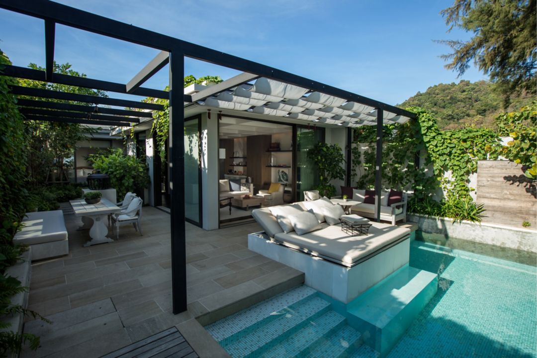 The living room and dining area of a beachfront resort villa in Phuket, including a big table and a couch, with a view of the ocean.