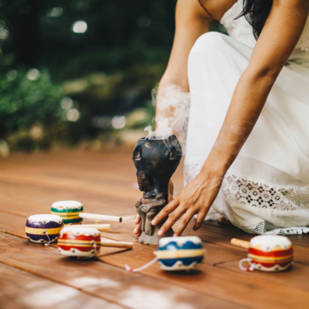 women in white dress kneeling with ceremonial drums and incense smoke for Rosewood Mayakoba's Marry Oneself Ceremony at Sense Spa