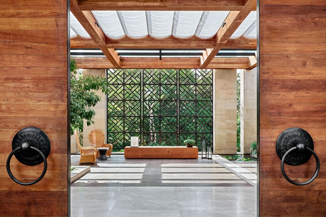 A resort entrance with wooden doors, a canopy, and a courtyard featuring a bench.