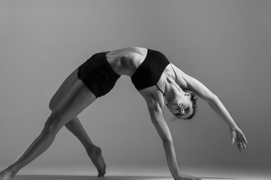 A woman performing a graceful yoga backbend pose.