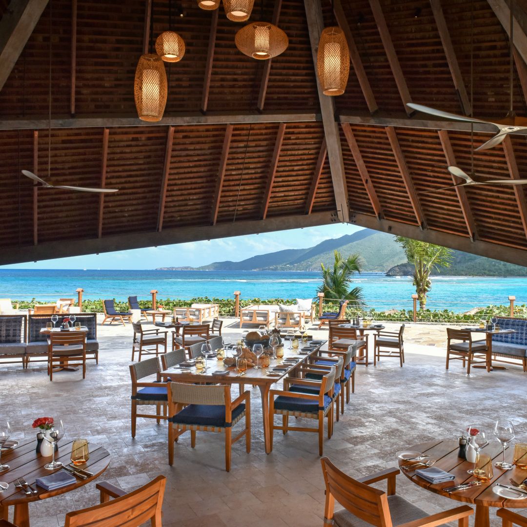 A waterfront restaurant dining area in Virgin Gorda featuring uniquely shaped vaulted roofs that invite the ocean breeze.