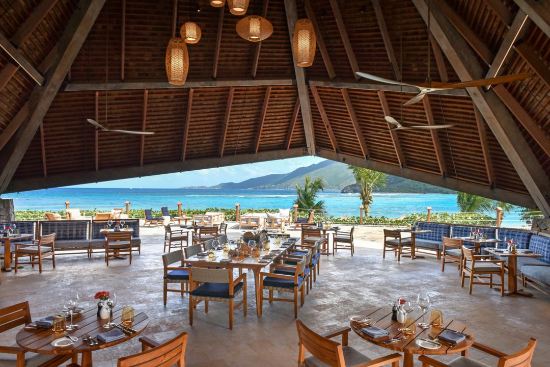 A waterfront restaurant dining area in Virgin Gorda featuring uniquely shaped vaulted roofs that invite the ocean breeze.