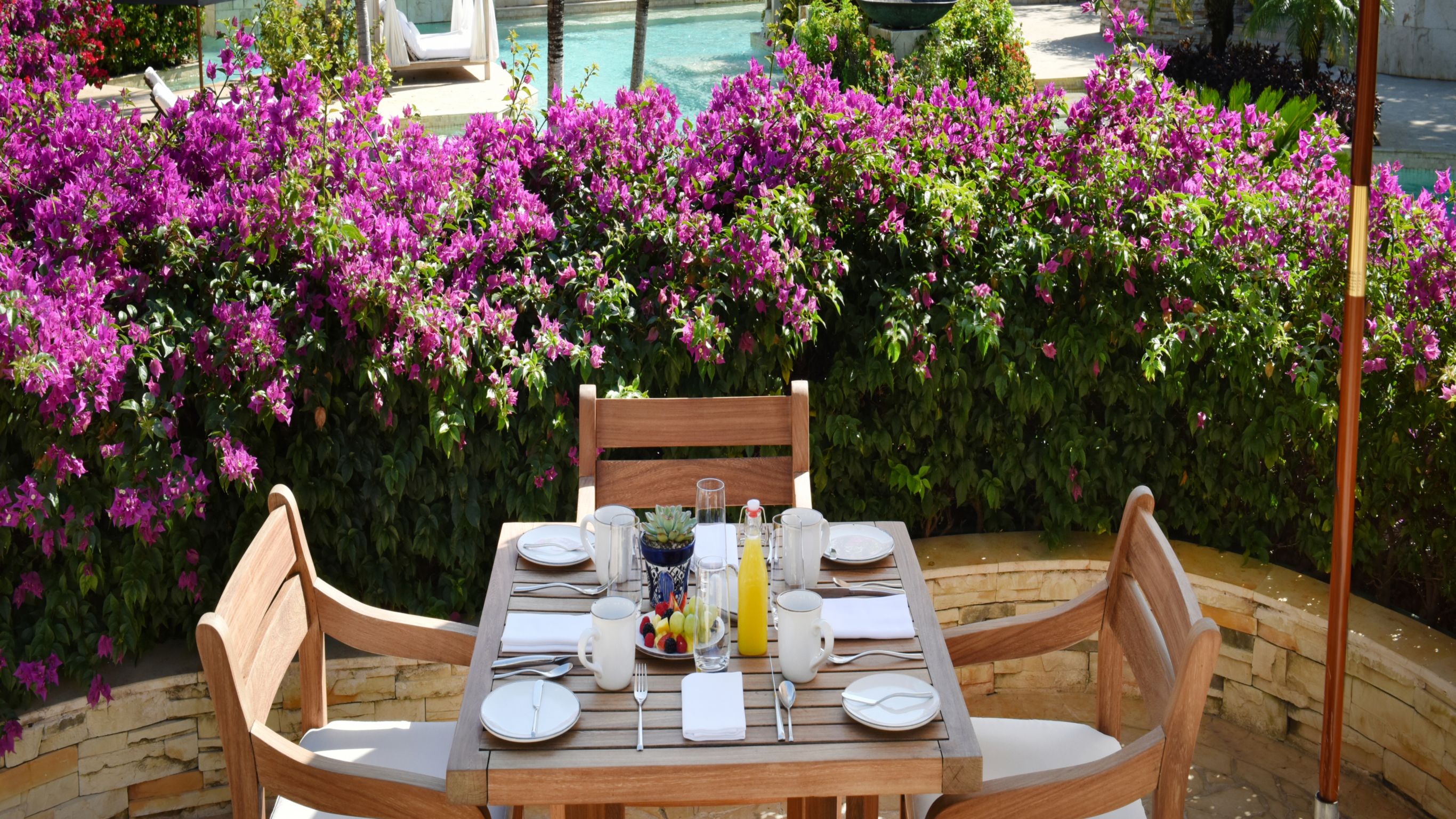 café da manhã servido no terraço ao ar livre com vista para a piscina do Casa del Lago e flores tropicais