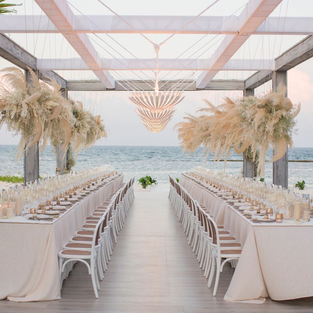 Two long tables overlooking beach set up for wedding reception