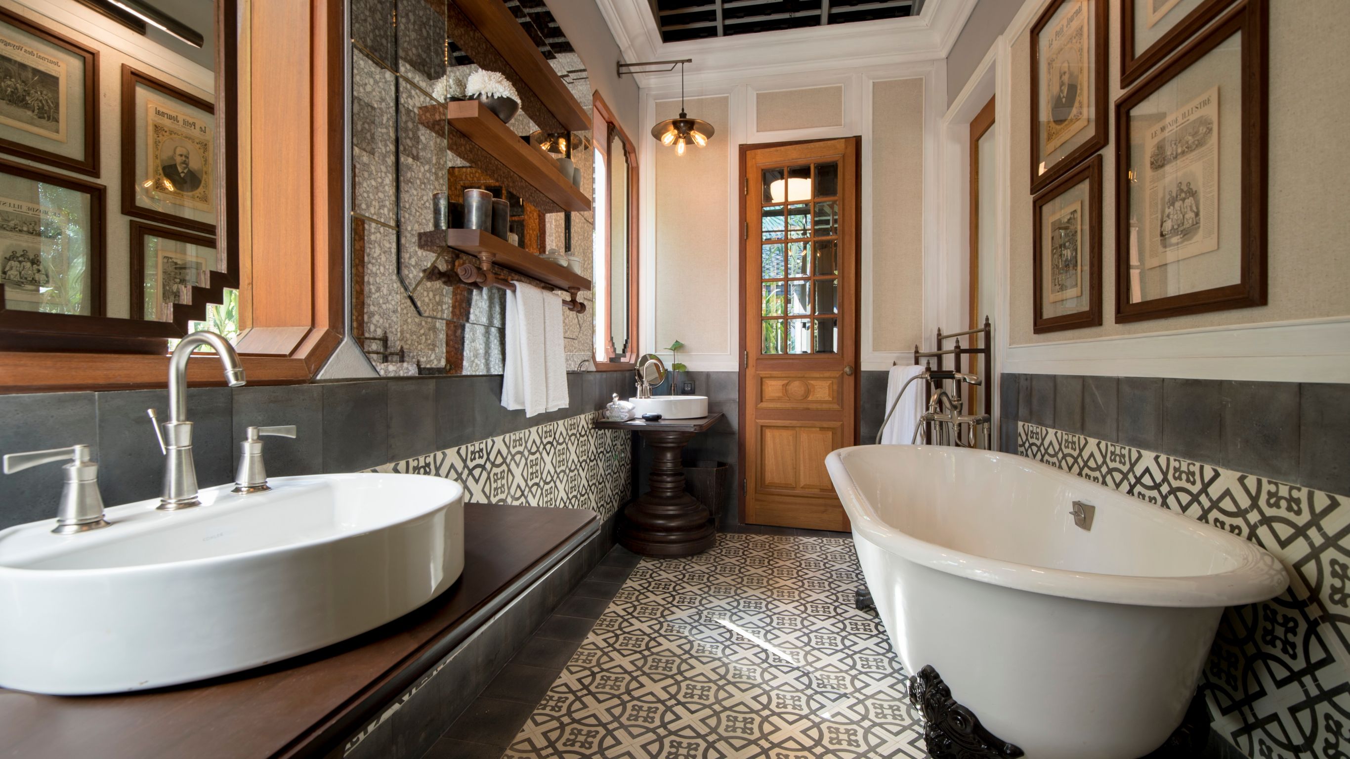 Luxury hotel bathroom designed by Bill Bensley with a white sink, a freestanding bathtub and patterned flooring in Luang Prabang