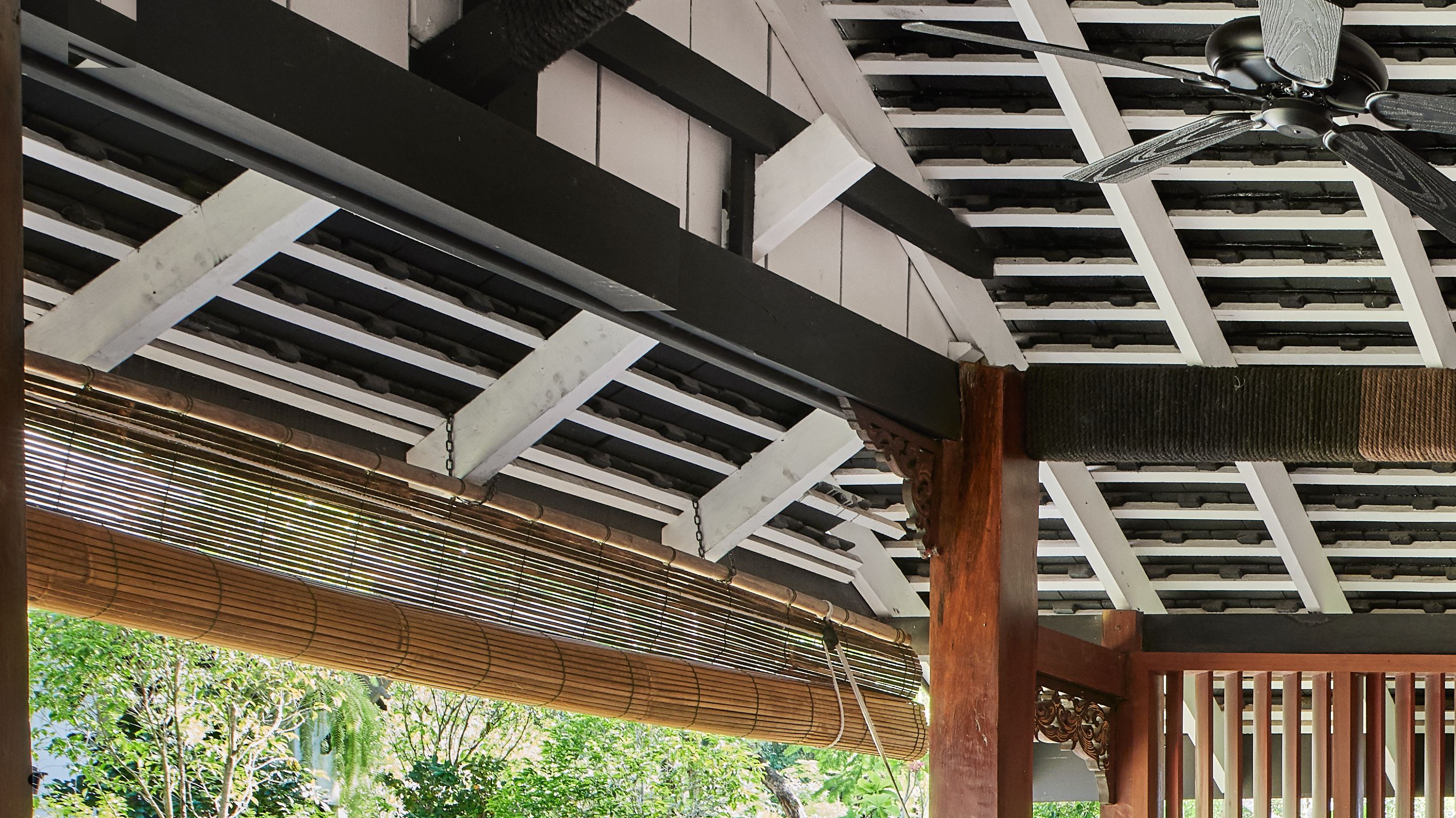 View of a hotel bedroom designed by Bill Bensley and an external seating area with a lounge sofa and chairs in Luang Prabang
