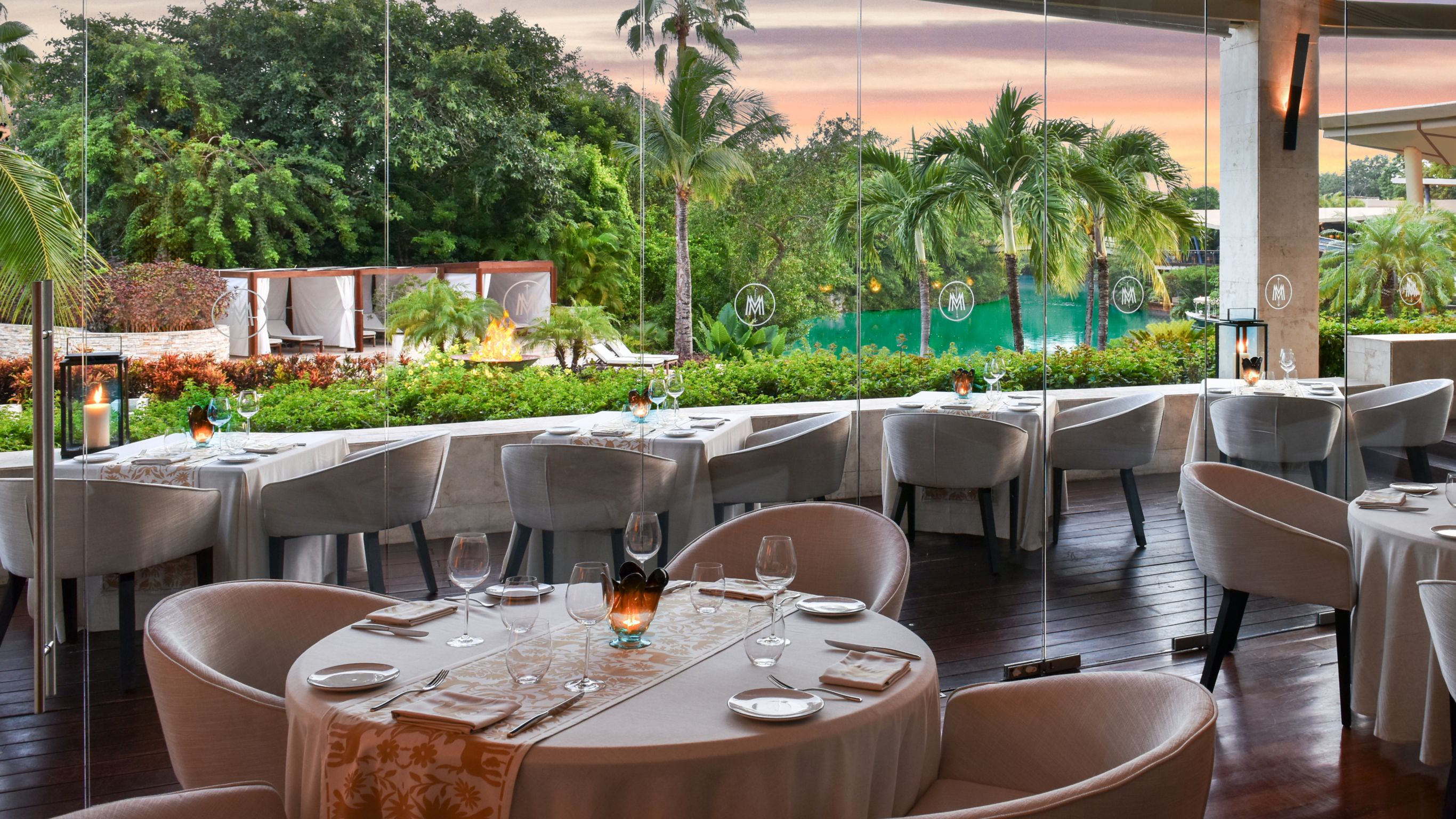 Casa del Lago restaurants indoor dining room with white table clothes overlooking palm trees and lagoon 