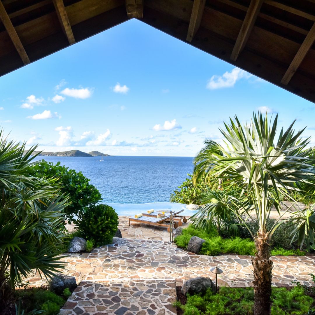 Scenic patio with ocean views, greenery, and an infinity pool.