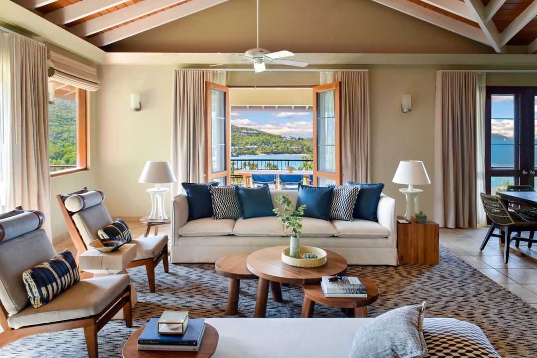 Cozy living room with a cream sofa, coffee table, and large windows offering a scenic ocean view.